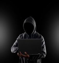 Cybercrime, hacking and technology crime. no face hacker with laptop on black background with...