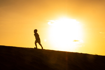 Silueta de niño Corriendo en el Desierto atardecer 