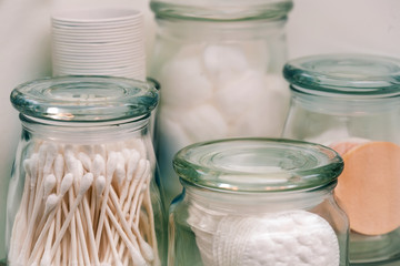 Sealed glass jars with makeup remover pads, cotton swabs and cotton balls for storage.