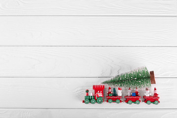 Toy of New Year tree and train on white wooden background