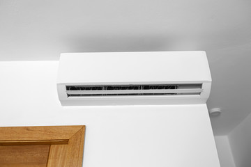Flat air conditioner on white wall in room