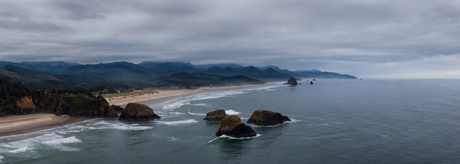 Cannon Beach, Oregon, United States. Beautiful Aerial Panoramic View of the Rocky Pacific Ocean Coast during a cloudy summer sunrise.