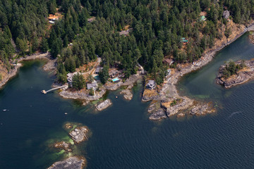 Naklejka premium Sunshine Coast, British Columbia, Canada. Aerial View of Residential Homes on the Rocky shore during a sunny and hazy summer morning.
