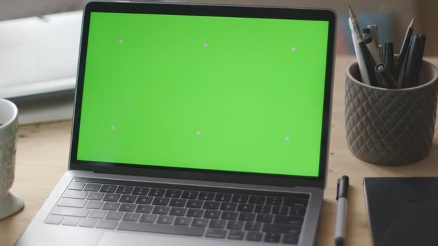 Modern laptop with green screen mock-up on working desk
