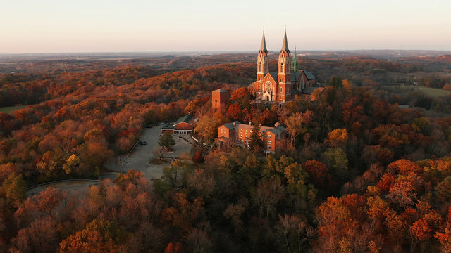 Aerial view of a church on the top of hill and autumn forest, red foliage . Fall season, autumn colors. Countryside, Wisconsin. Drone shots at sunset