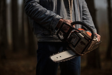 Lumberman work with chainsaw in the forest. Lifestyle work.  Male hands with a saw in the woods....