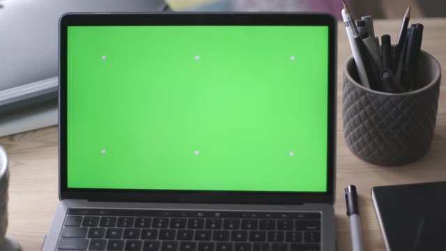 Modern laptop with green screen mock-up on working desk