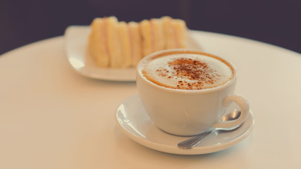 cup of hot cappuccino coffee with sandwiches for breakfast in the morning.
