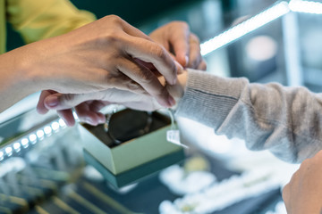 Obraz premium Thai female jewelry seller put gold bracelet on a customer hand for trying or fitting.