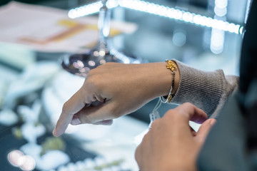 Thai female customer  put gold bracelet on her hand for trying or fitting.