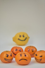 Concept of bullying, discrimination. Group of laughing emoticon faces and one alone look sad and depressed. Lemmons and mandarines. Cyber bullying on internet.