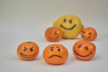 Concept of bullying, discrimination. Group of laughing emoticon faces and one alone look sad and depressed. Lemmons and mandarines. Cyber bullying on internet.