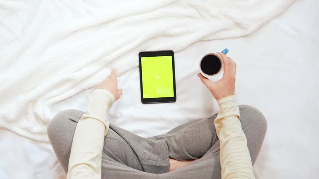 top view man sitting on the bed using digital tablet with green screen guy in bedroom in the morning