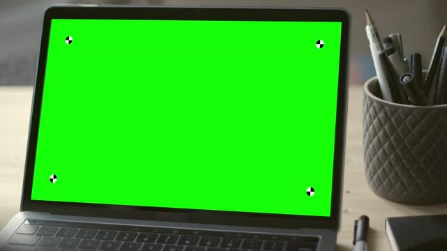 Modern laptop with green screen mock-up on working desk