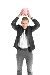 Young man breaking piggy bank on white background