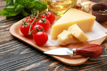 Plate with tasty Parmesan cheese and tomatoes on wooden background