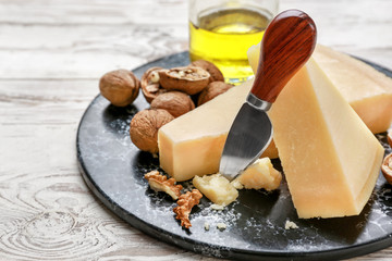 Tasty Parmesan cheese, walnuts and knife on wooden background