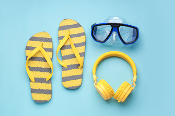 Flip-flops, snorkeling mask and headphones on color background