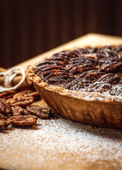 Fresh baked maple walnut pecan pie on a brown wooden background