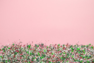 Colorful christmas sprinkles on edge of pink background