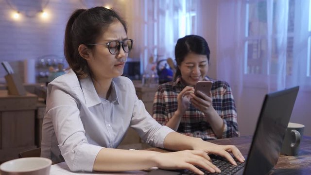 Angry Worker Scolding Noisy Roommate And Telling To Leave At Kitchen Table At Home In Night. Business Woman Stay Up Late Over Work On Notebook Computer. Annoying Friend Laughing Use Mobile Phone