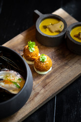 Haute cuisine - noodles with oysters filled by freezy ozone , croutons and yellow sauce on a wooden plate with dark background