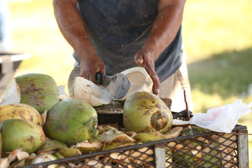 Man chopping green coconut with a machete