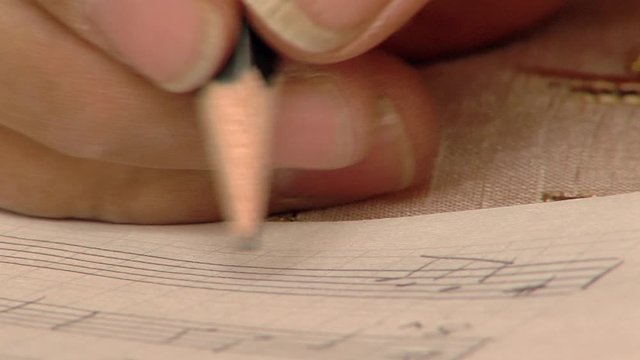 Male Hand writing Notes with Pencil on Sheet Music. Close-Up.   