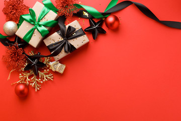 Beautiful minimal christmas golden black red decor and paper craft gift box with satin black ribbon on red background. Flat lay design. Copy Space. Horizontal, coupon, sale