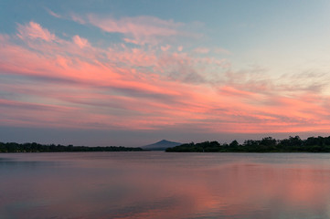 Beautiful sunset sky with colorful pink clouds over river