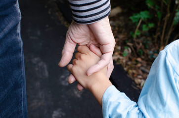 Grandmother's hands holding hands with grandchild during walk