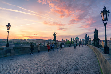 Tourists at sunrise on Charles Bridge landmark in Prague
