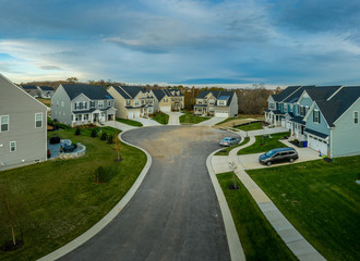 Aerial view of new construction street with luxury houses in cul-de-sac upper middle class neighborhood American real estate development in the USA with blue sky	