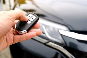 Man hand holding the car remote, he push the remote control to open the car door