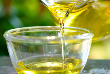 Pouring olive oil in the a glass bowl at stone kitchen and inside green garden view. Prepare for cooking concept. Healthcare and Beauty Concept.