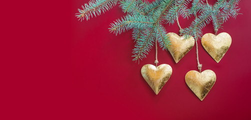 Golden metal hearts, Christmas toys, hung on a spruce branch. Christmas photo.