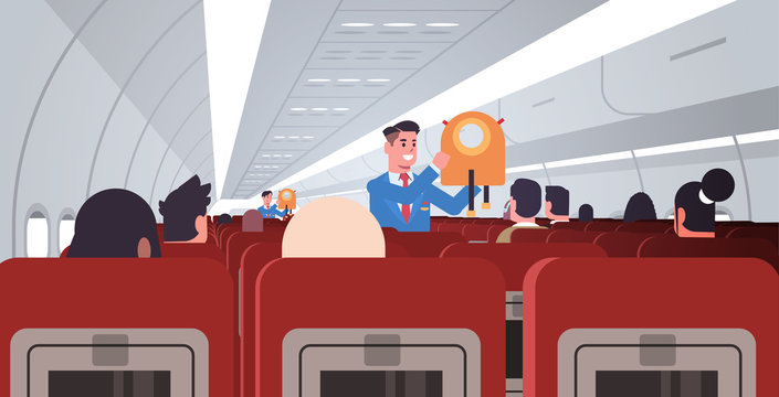 steward explaining for passengers how to use jacket life vest in emergency situation male flight attendants in uniform safety demonstration concept modern airplane board interior horizontal flat