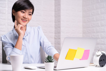 Happy woman sitting at home office working using computer laptop