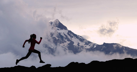 Running woman athlete silhouette trail running in mountain summit background