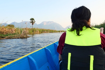 An Asian man wearing a life jacket sitting in a passenger boat, Thai Taxi Boats with Personal flotation device, The ship was traveling in lake at Khao Sam Roi Yot National Park , Thailand