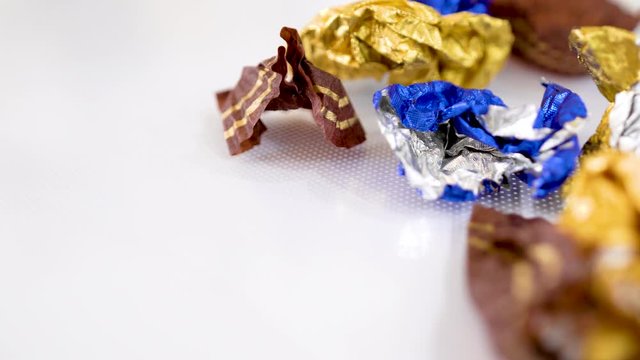 After party, finished candy, full of wrapping paper on white background, panning shot