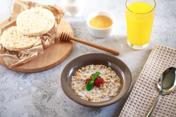 Granola with milk and berries in a plate, bread rolls with honey and orange juice. Healthy and tasty breakfast. Baked Muesli.