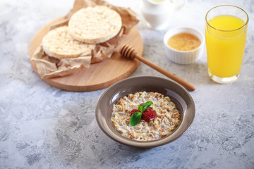A healthy and dietary breakfast. Baked granola with milk and raspberries in a plate, whole grain breads and freshly squeezed juice. Delicious muesli.