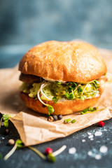 Fresh tasty burgers with roasted chicken, potato, micro greens and different herbs on the rustic background. Selective focus. Shallow depth of field.