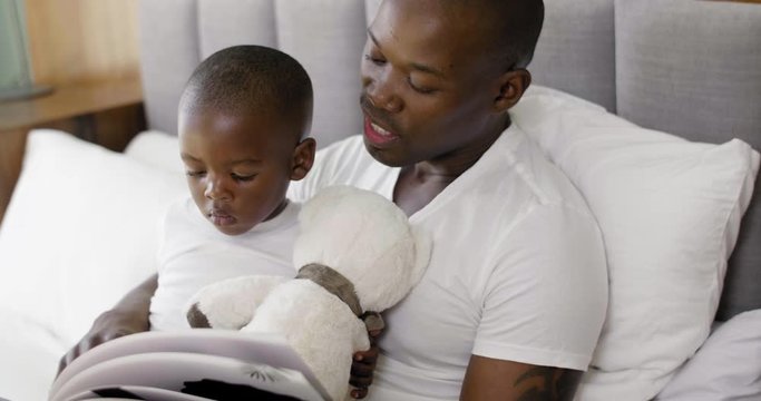 Father reading stories to his child in bed, involved dad parenting habit