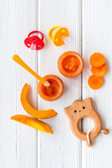 Orange baby food. Puree near pumpkin and carrot on white wooden background top view