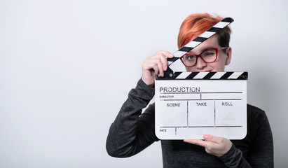 redhead woman holding movie  clapper on white background