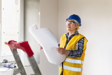 Woman Builder in the room of the house making repairs.