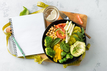Vegan healthy balanced diet. Vegetarian buddha bowl with blank notebook and measuring tape....
