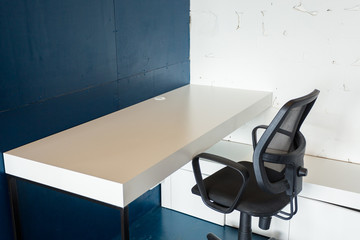 Loft style office with white brick walls and concrete columns. There is a meeting area with a large white table with black chairs